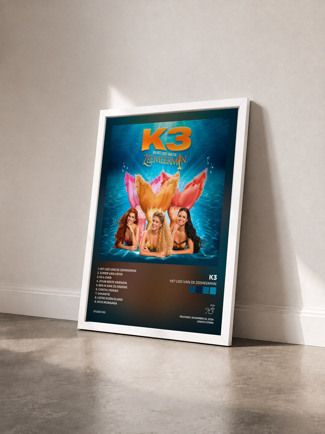 #blanc Tableau de l'album Het Lied van de Zeemeermin de K3 vu de trois quarts, cadre blanc