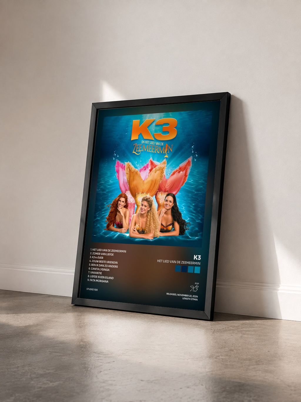 #noir Tableau de l'album Het Lied van de Zeemeermin de K3 vu de trois quarts, cadre noir