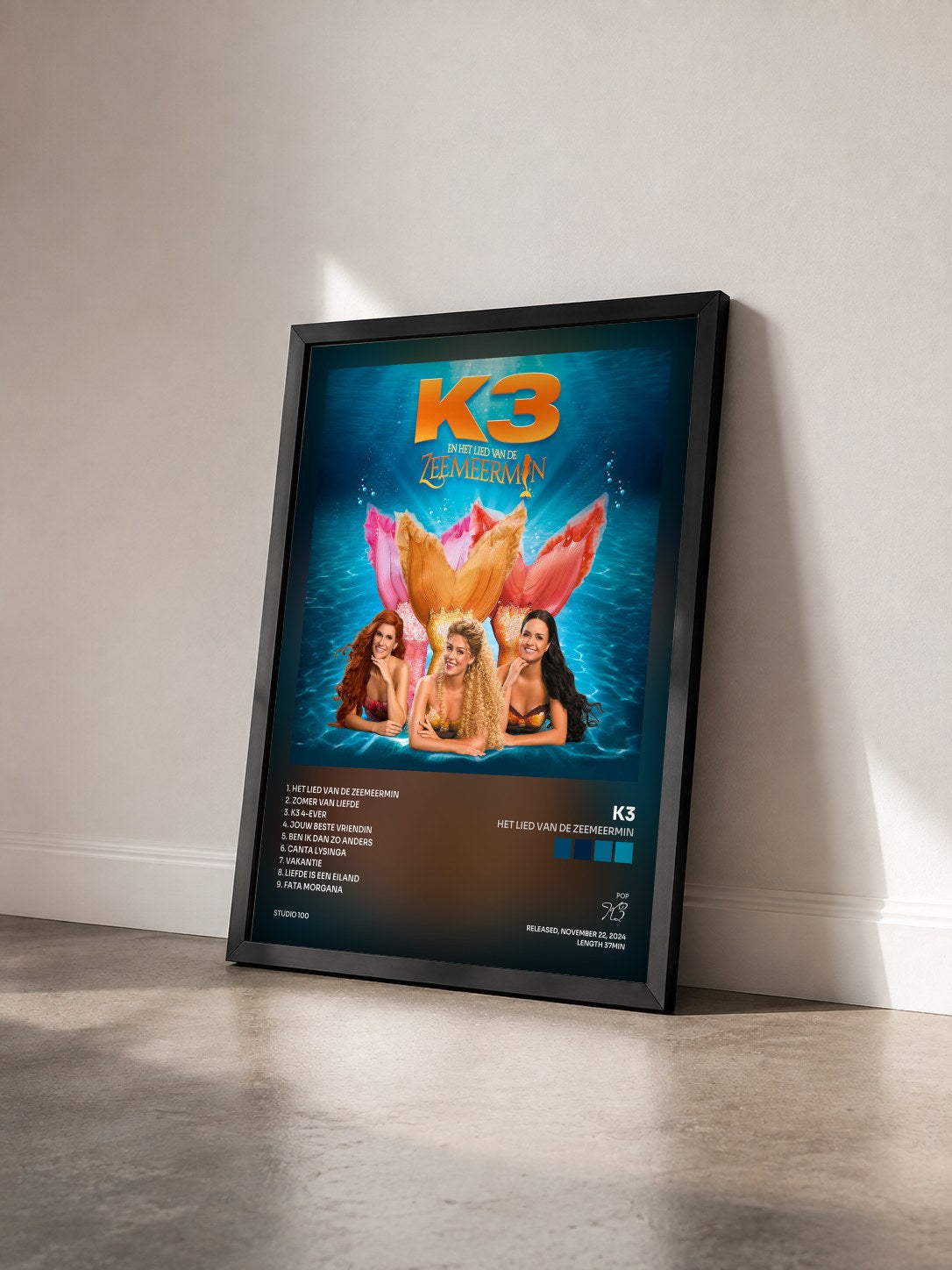 #noir Tableau de l'album Het Lied van de Zeemeermin de K3 vu de trois quarts, cadre noir